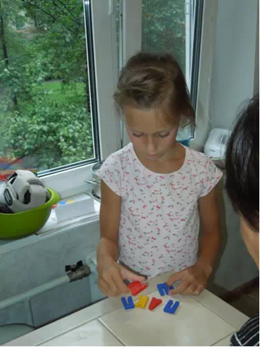 Девочка Маша выполняет задание квеста из букв магнитиков с холодильника