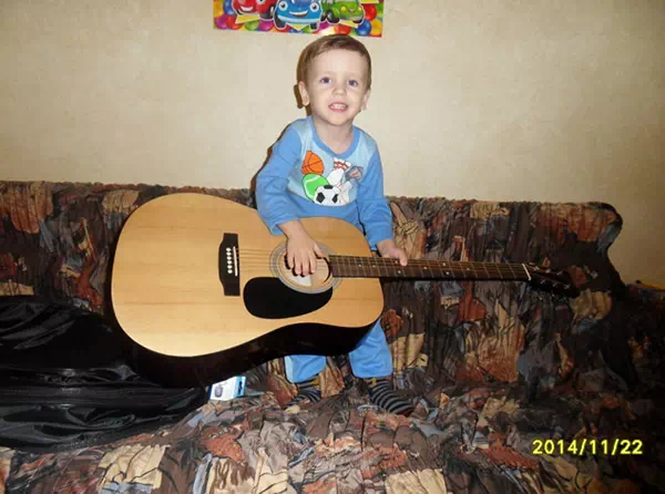 Ребенок играет на папиной гитаре