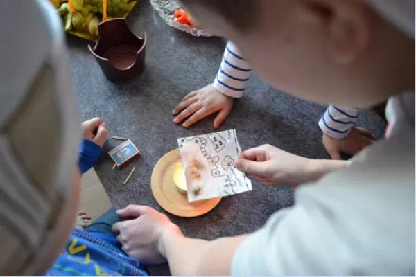 Дети держат карту над свечкой